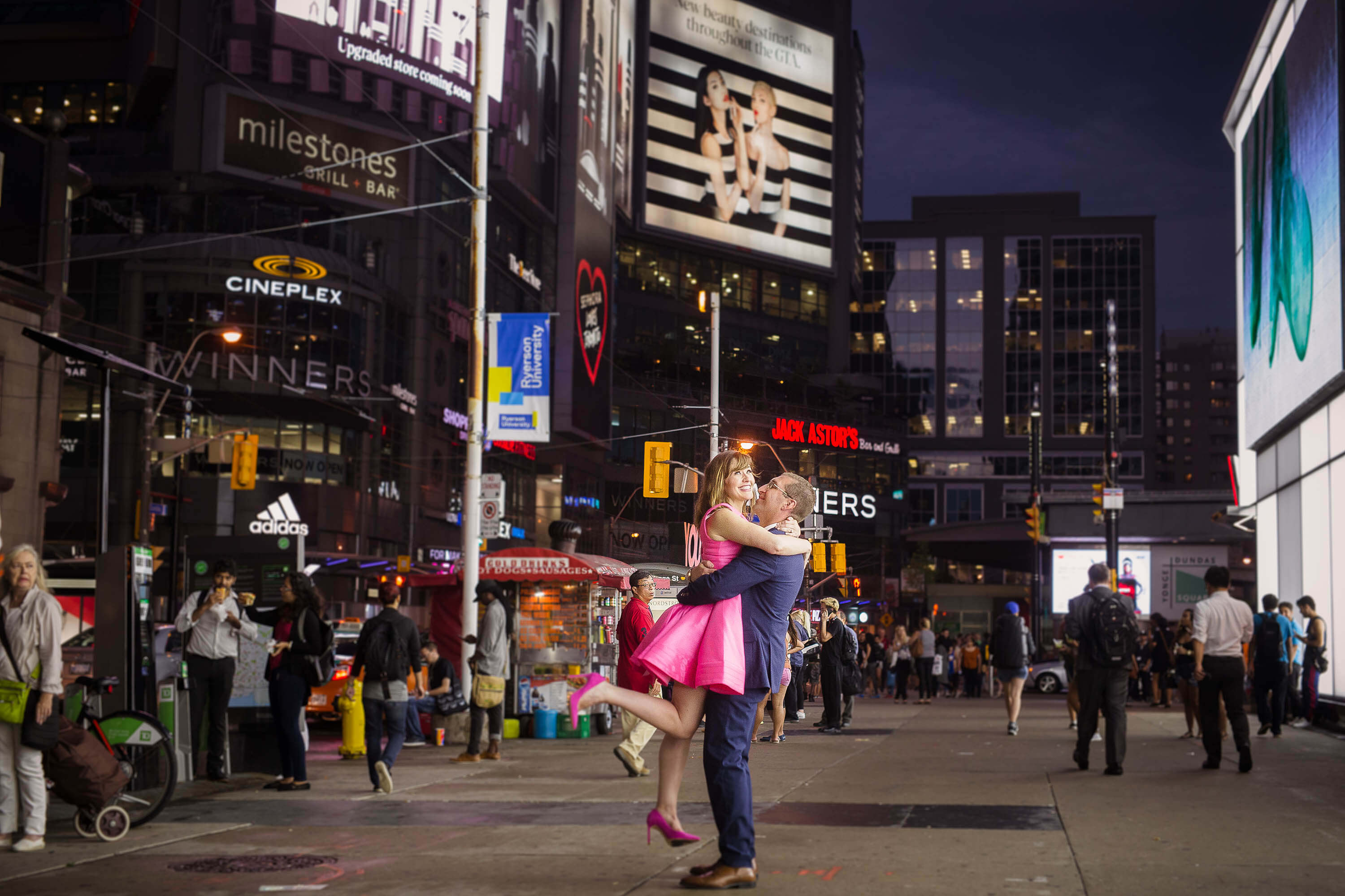 Toronto's Dundas Square engagement session with male holding his fiancé in the air