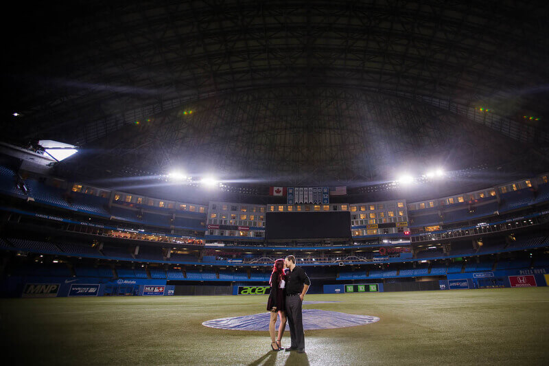 Toronto's Rogers Centre engagement session. Spotlights highlighting the couple sharing a kiss on the field. 