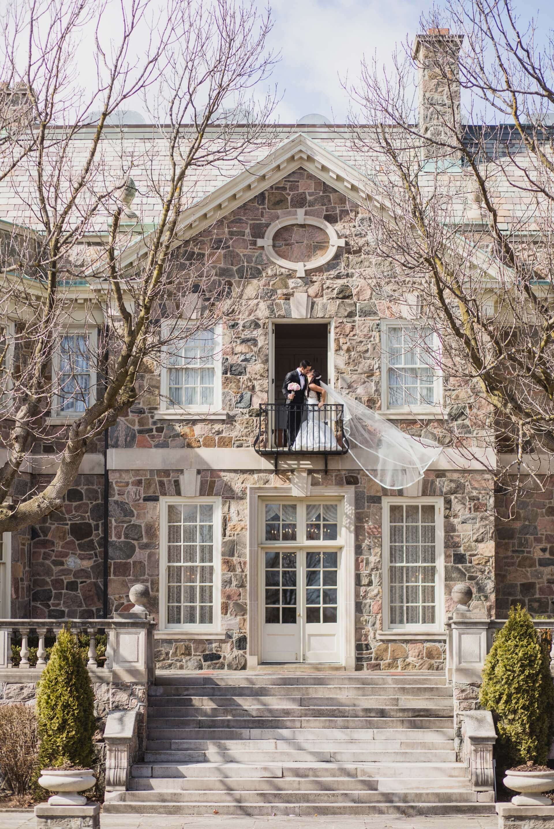 Toronto bride and groom share a kiss on a balcony. 