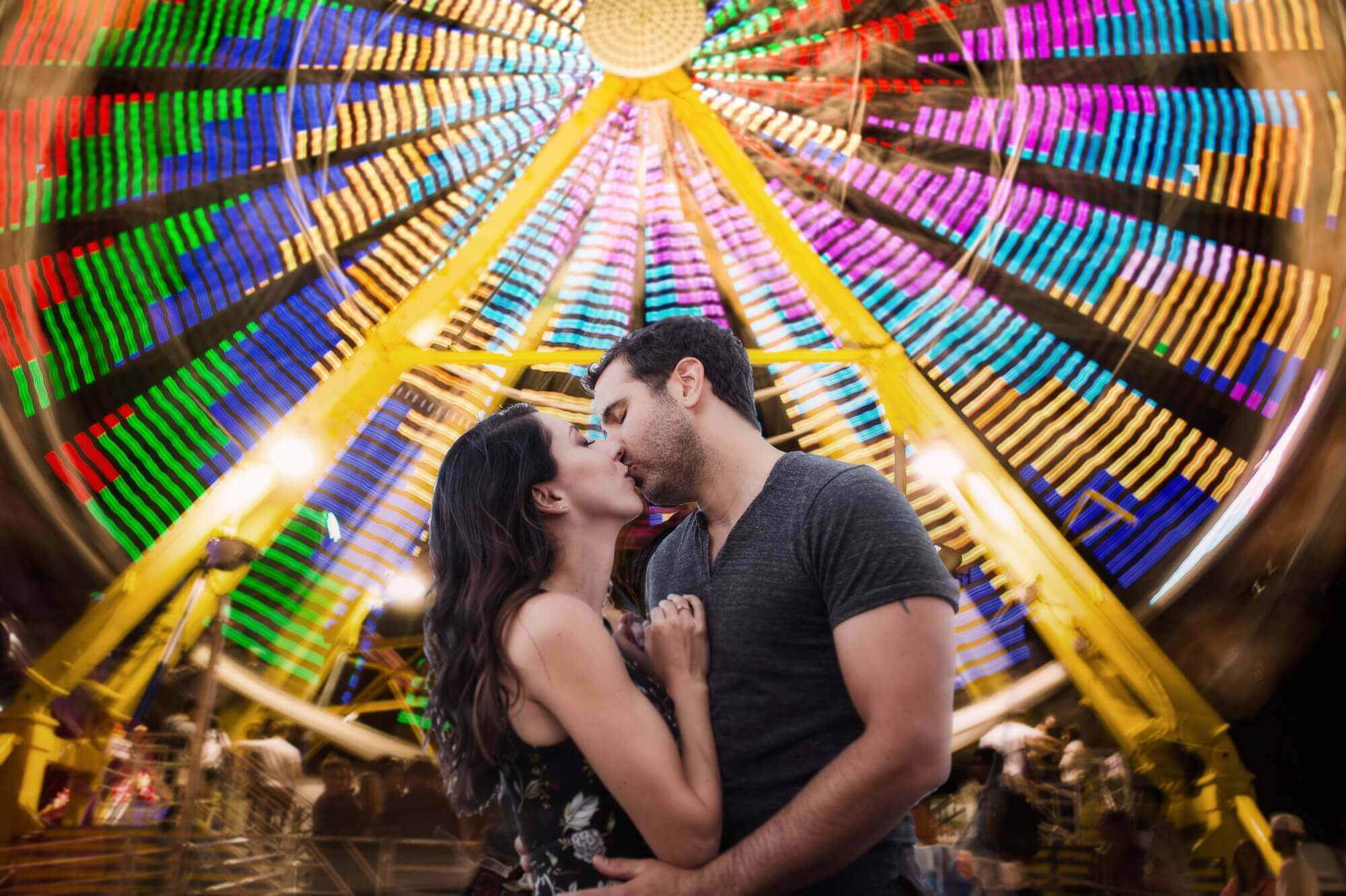 Toronto's CNE farris wheel used as a stunningly colourful background for a couple sharing a kiss
