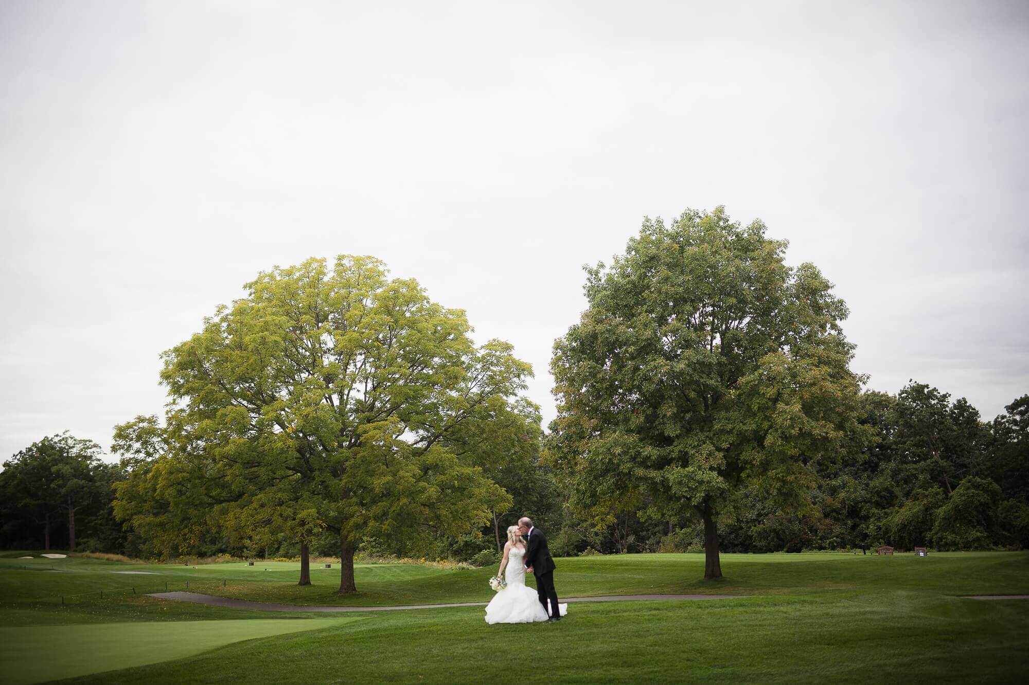 Wide portrait of the bride and groom out on the green at Lambton Golf & Country Club