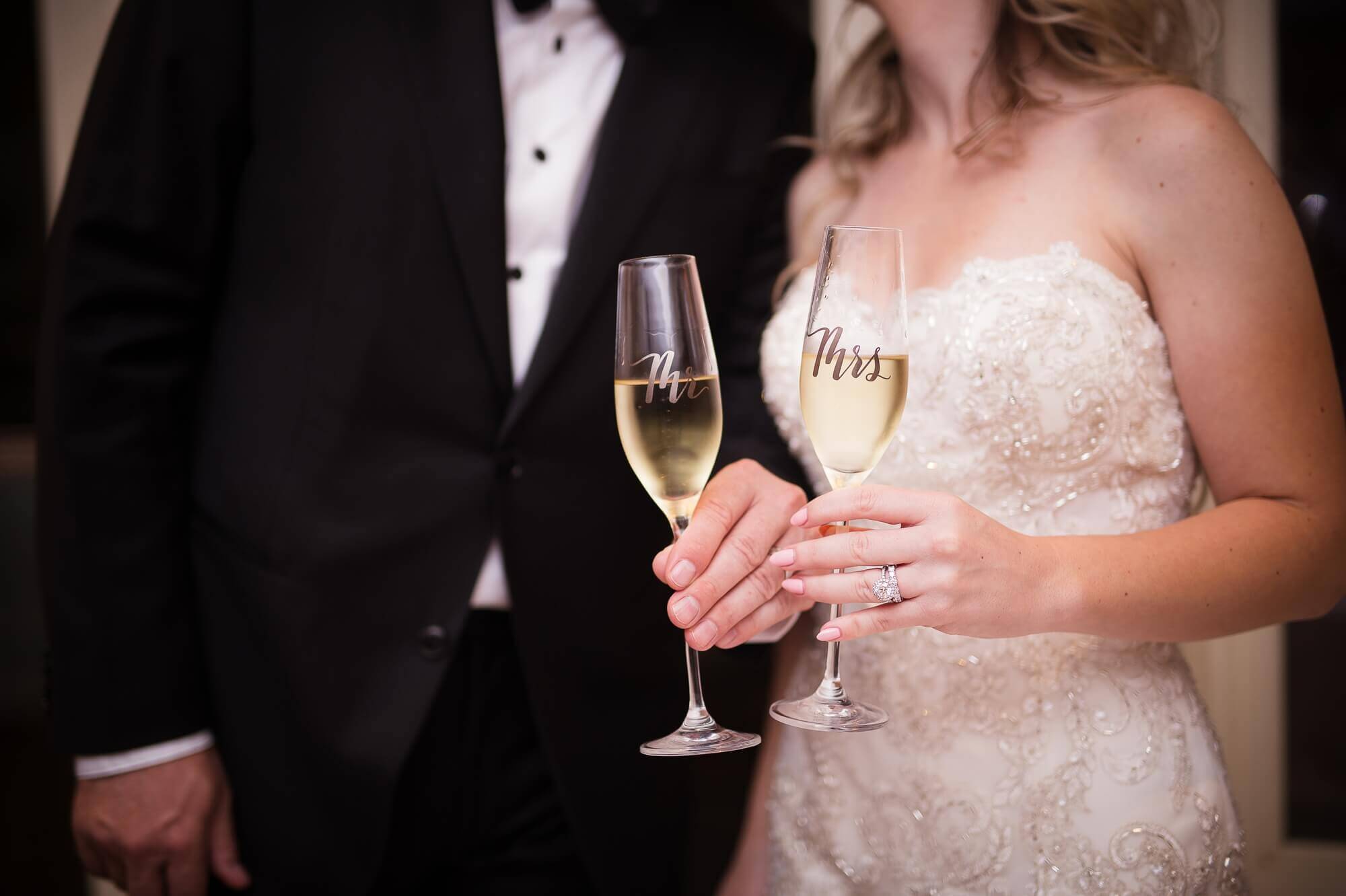 Details of the bride and groom holding their champagne glasses with wedding rings showing at Lambton Golf & Country Club