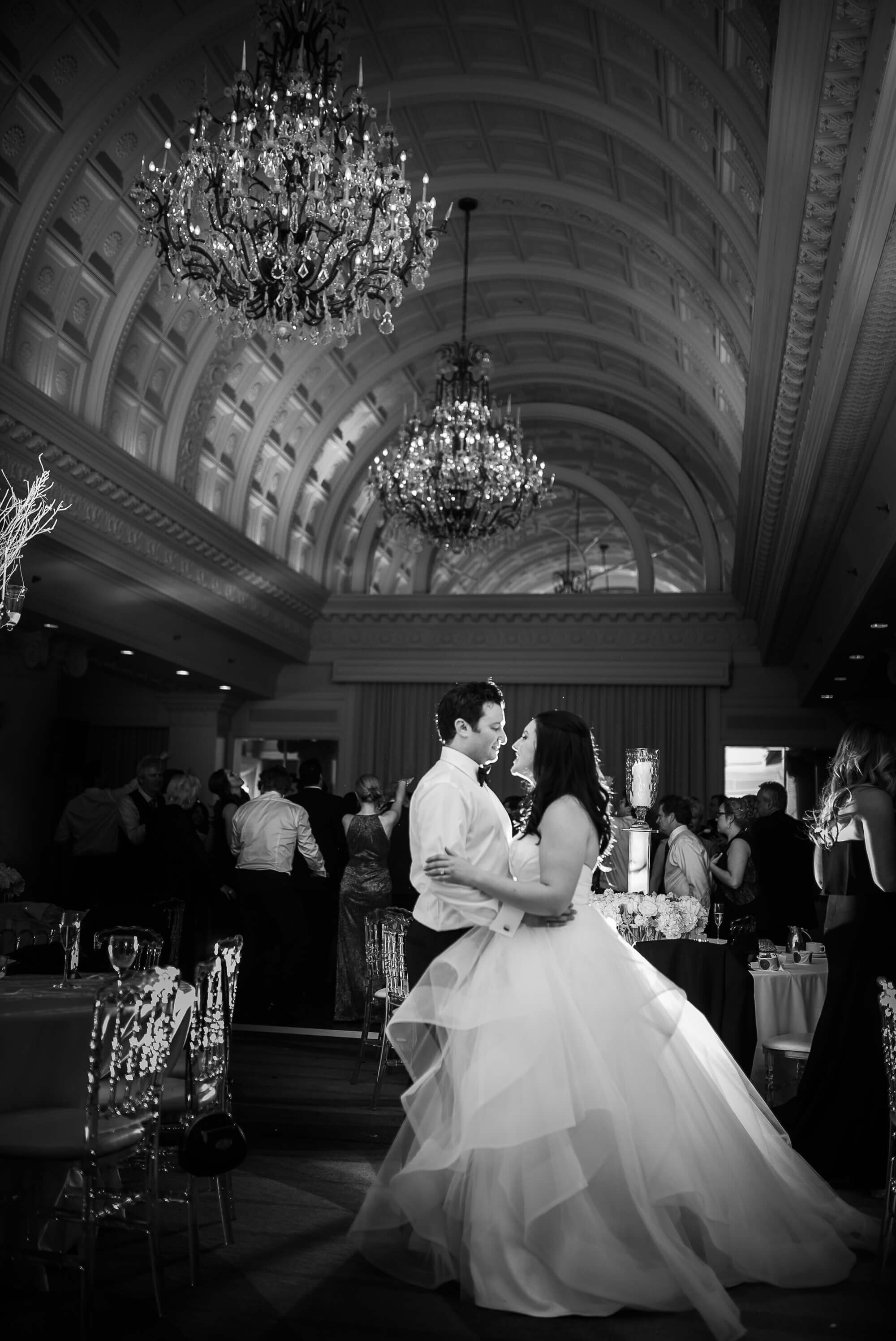 Luminous black and white portrait of the bride and groom dancing underneath the chandeliers at the Omni King Edward Hotel in Toronto