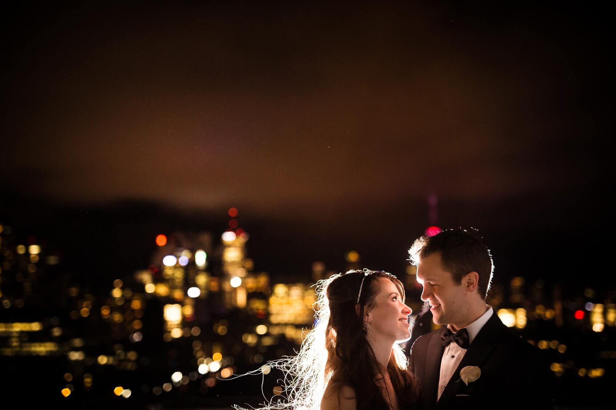 Portrait of the bride and groom on the balcony of the Fairmont Royal York, with a background sky illuminated by the city lights of Toronto