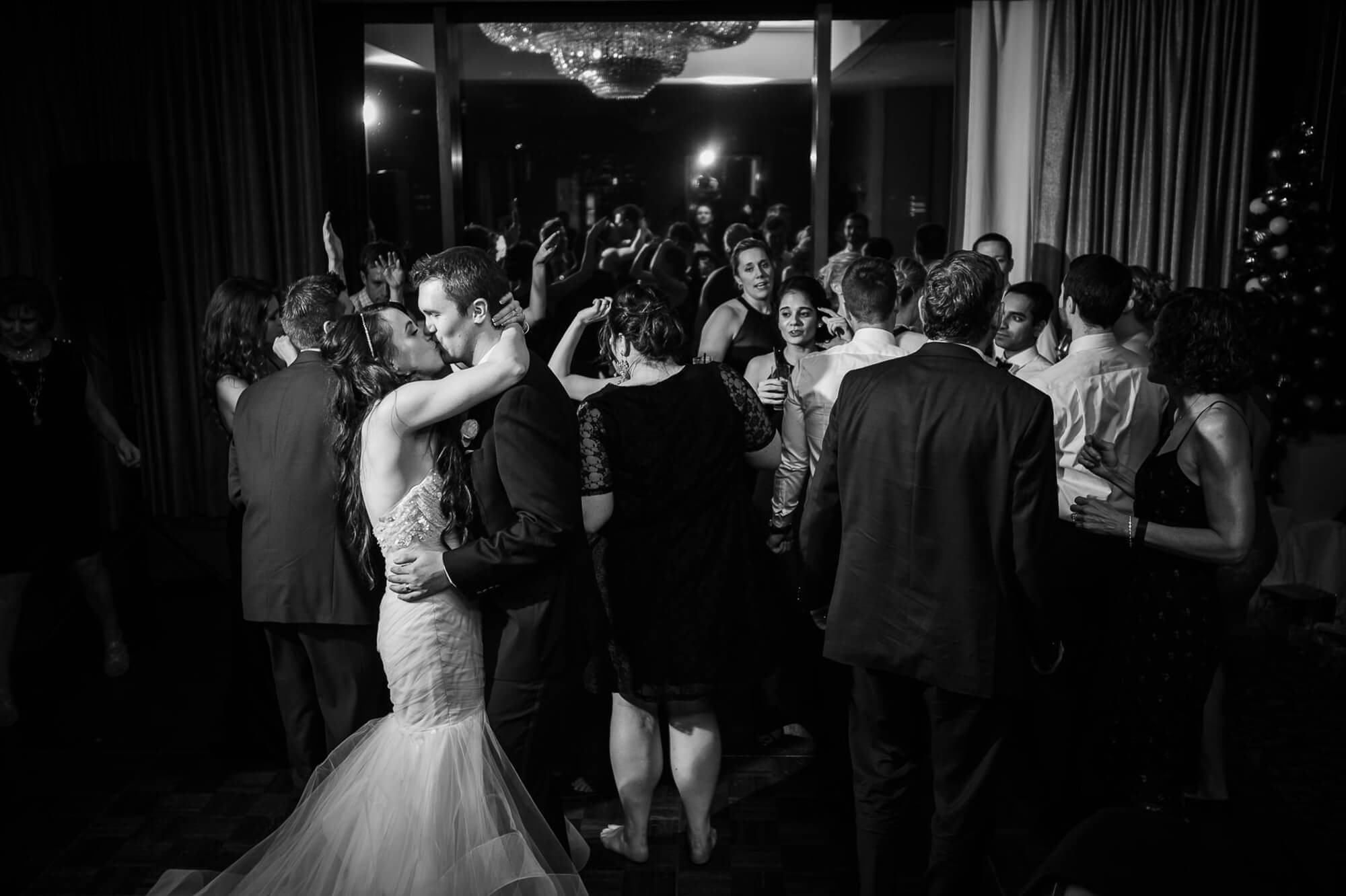 Intimate black and white portrait of the bride and groom kissing in the middle of their guests at the Fairmont Royal York, Toronto