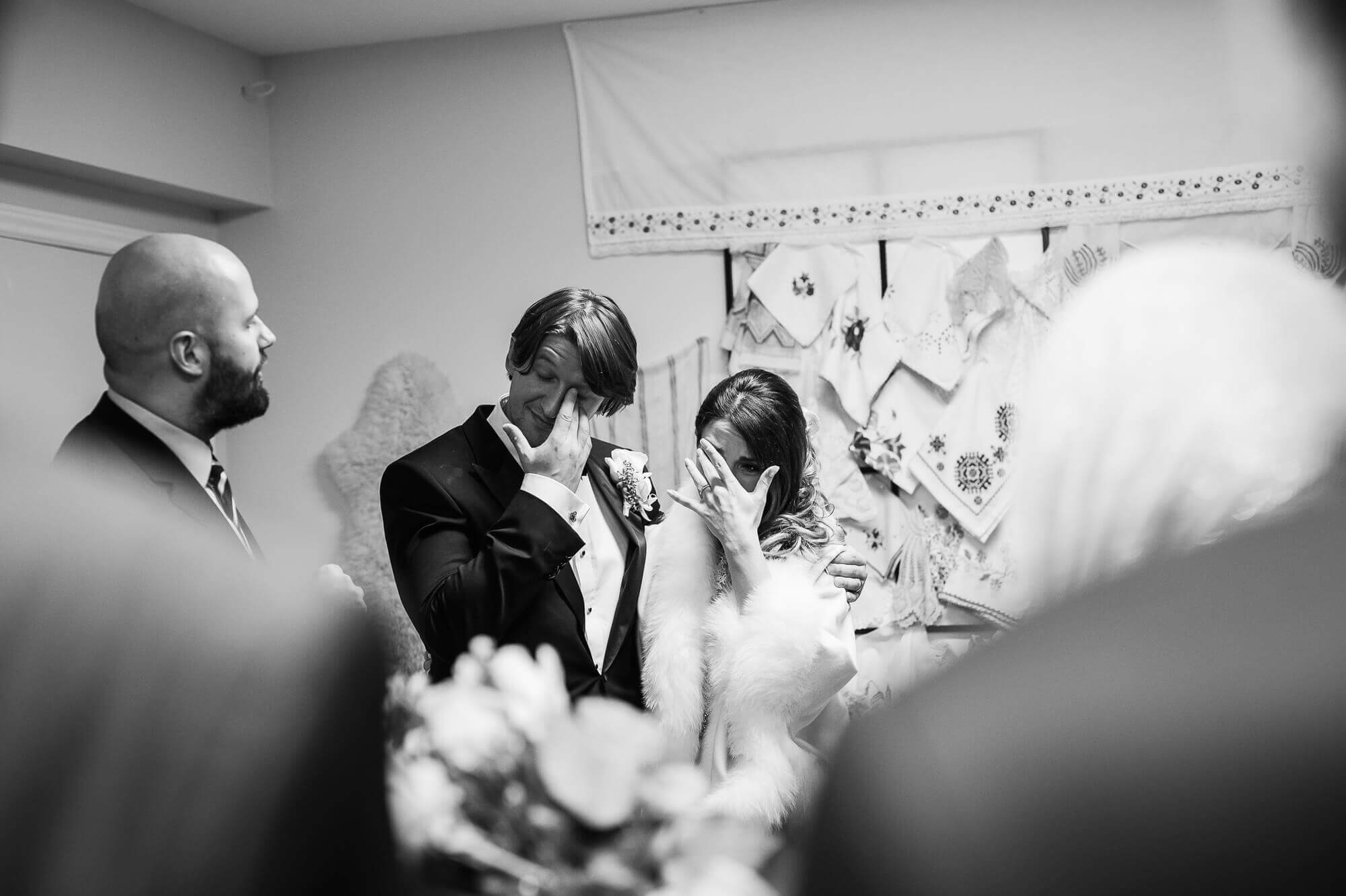 beautiful black and white portrait of the bride and groom wiping away some tears during their ceremony