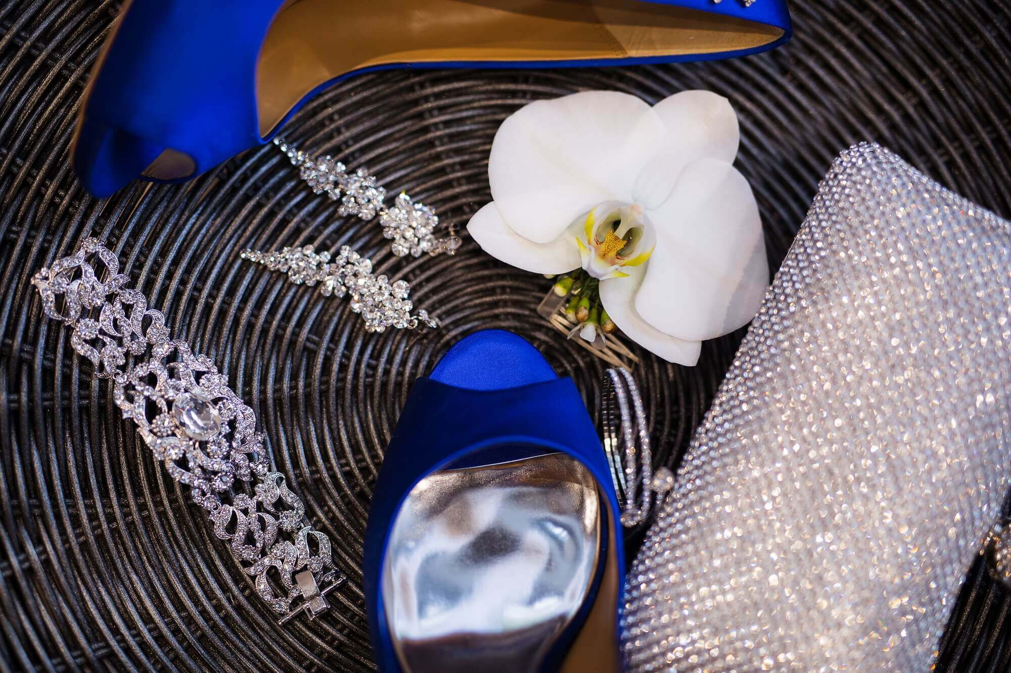 Details of the bride's wedding jewelry, sparkling clutch and blue wedding shoes