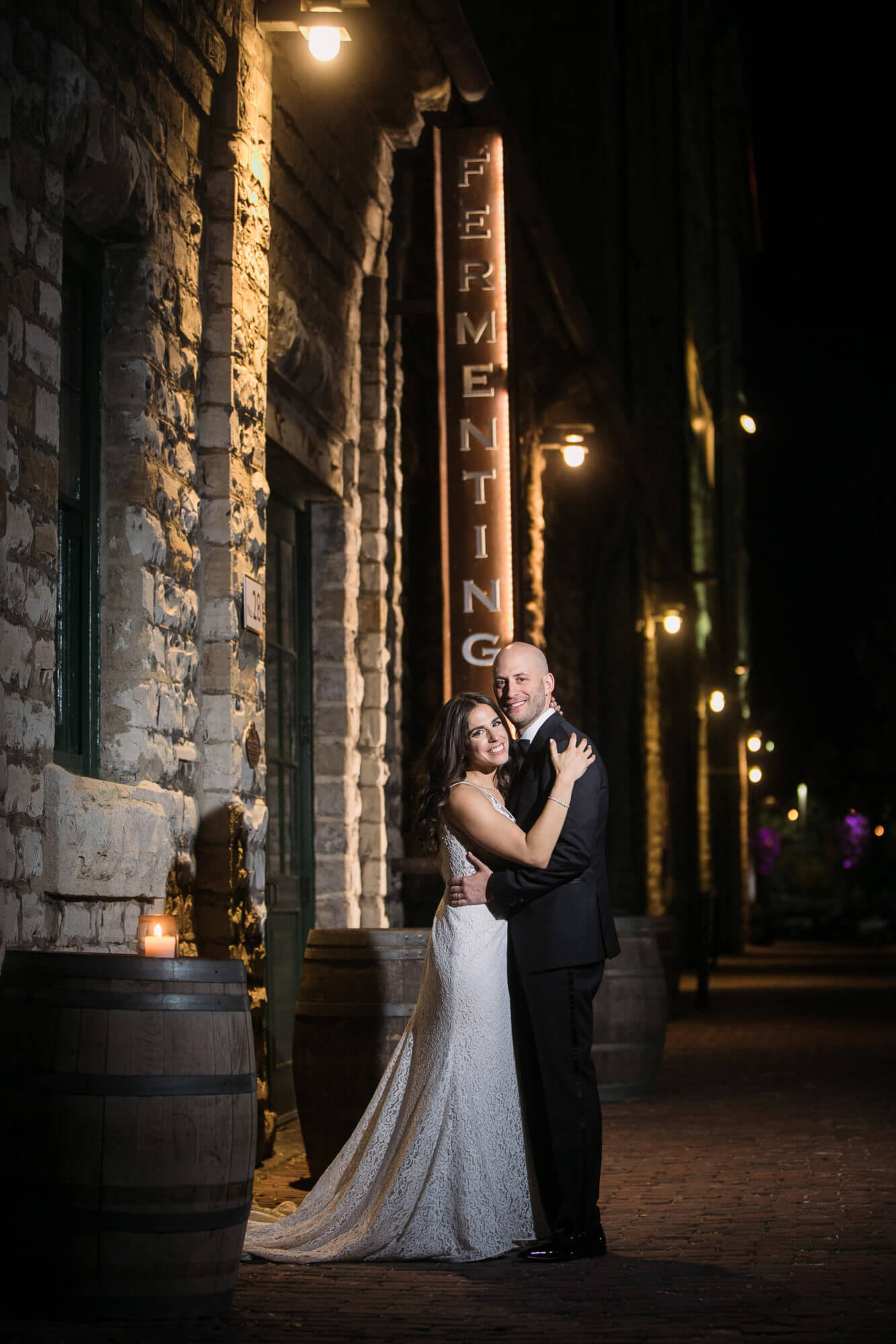 Rustic portrait of the bride and groom outside their wedding venue at Details of the wedding reception tables, lit candles and flower centrepieces, decorated at The Fermenting Cellar in Toronto