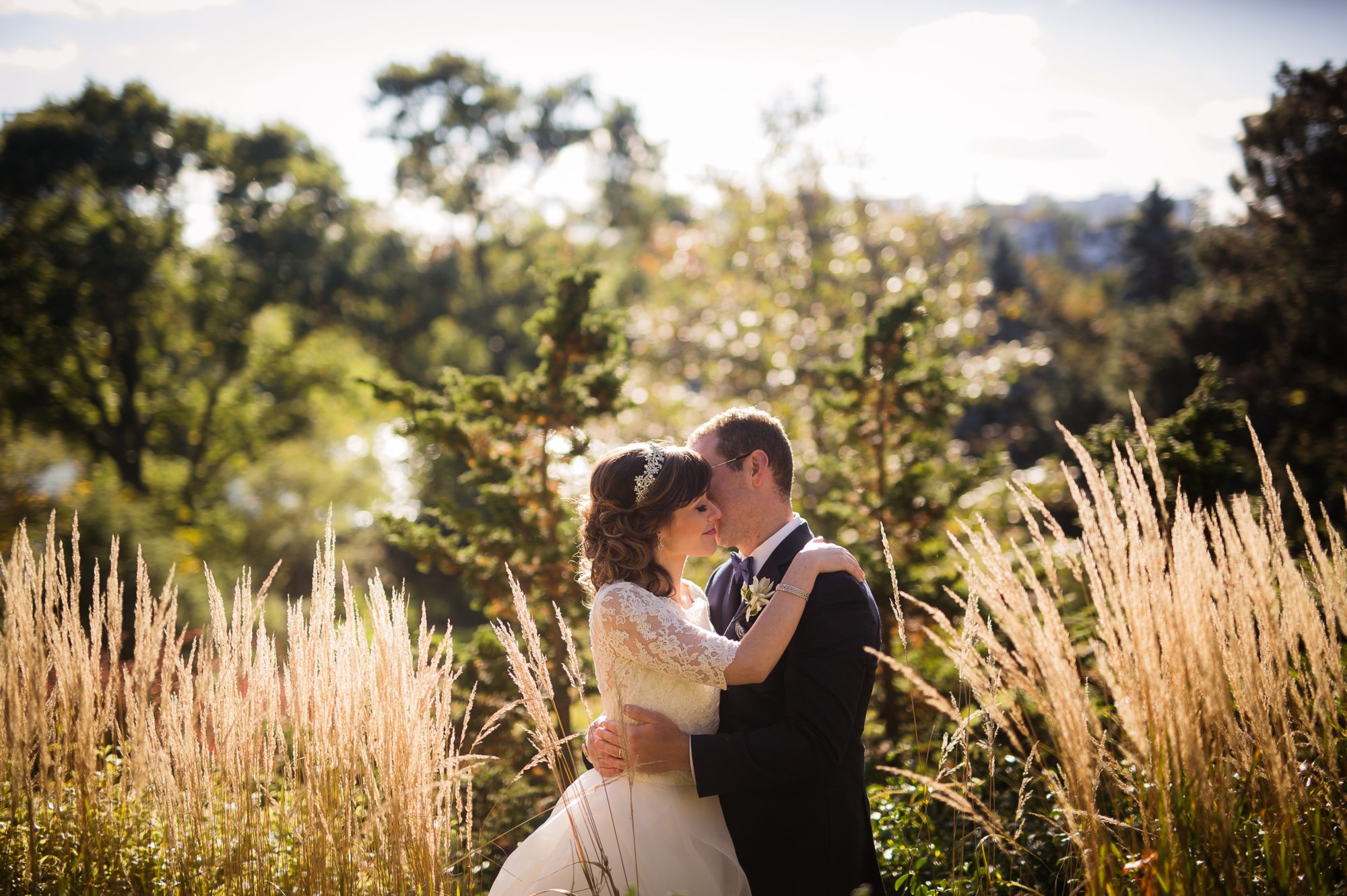 Bride and groom holding one another amongst an overgrown field in Toronto