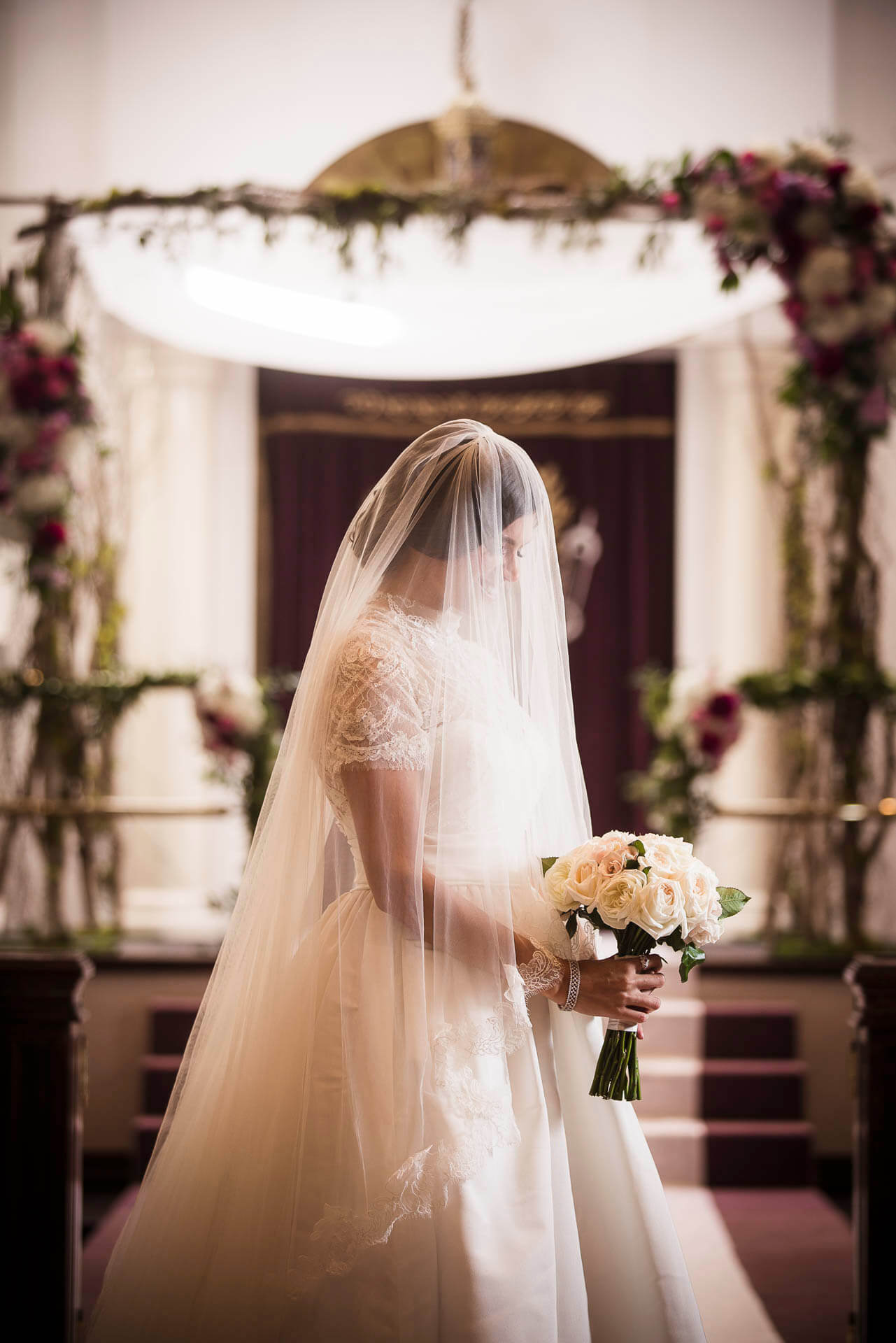bride with veil over face and bouquet